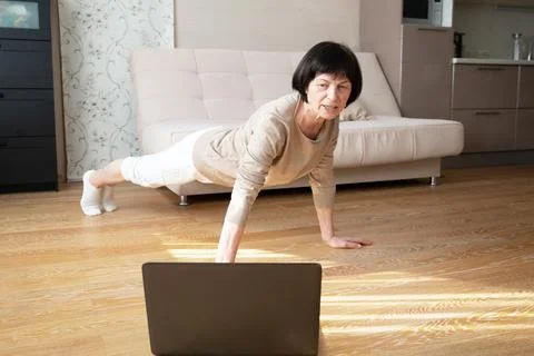 An active elderly caucasian does plank exercises at home on the floor in front Stock Photos