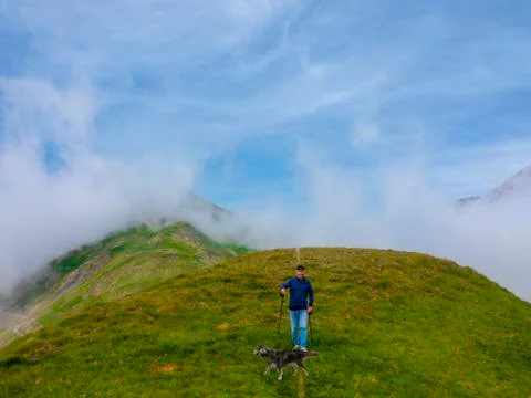 An active elderly man does walks in the mountains with his dog. Stock Photos