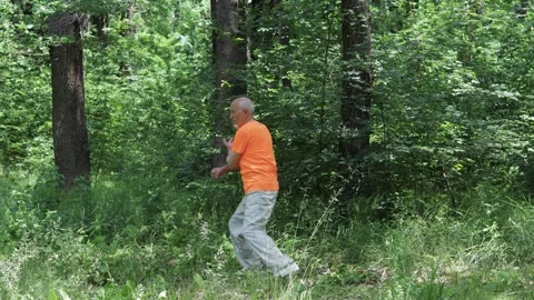 Active elderly man doing formal exercises against nature backdrop Video stock 314494171