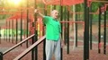 Active elderly man in green t-shirt exercising in outdoor gym HD Footage