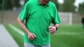 Active elderly man in green t-shirt runs around a football field HD Footage