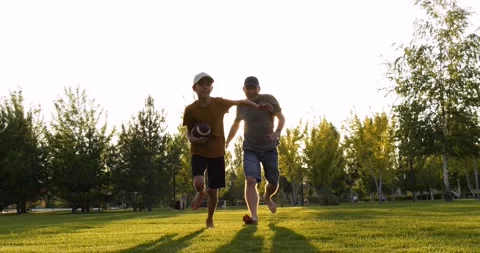 Active father chases running son with rugby ball. Sporty father races with boy Stock Footage 329865879