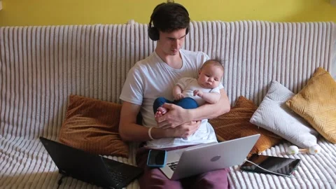 Active father, freelancer at home office Multi-tasking at work holds a child Stock Footage 153616112