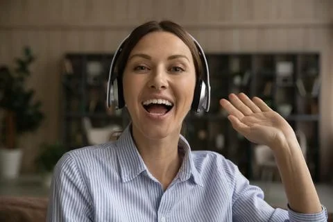 Active female blogger in headphones look at camera greet audience Stock Photos