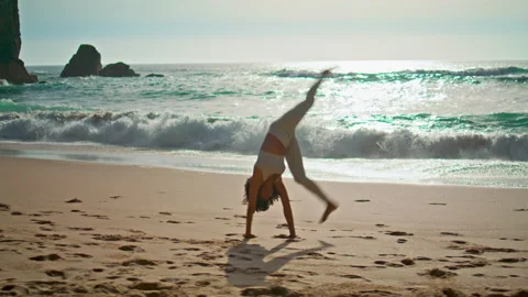 Active girl making gymnastics elements in front beautiful ocean waves sunny day. Stock Footage 215181075