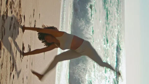 Active girl making gymnastics elements in ocean waves sunny day vertical shot Stock Footage 243138052