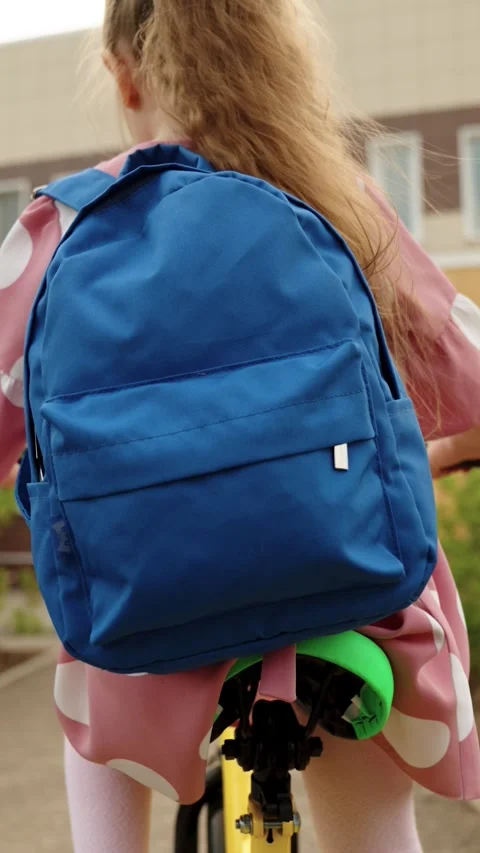 Active girl pupil backpack driving cycle arriving to elementary school campus Stock Footage 276512653
