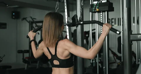 Active girl training upper back and arms on fitness machine Stock Footage 134248864