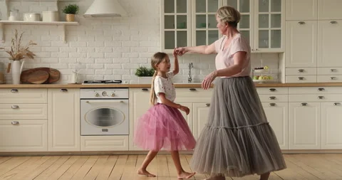 Active granny dance waltz with little granddaughter in kitchen Stock Footage