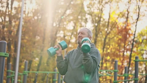 An active grey-haired elderly man in his retirement age doing exercises with Stock Footage 255714957