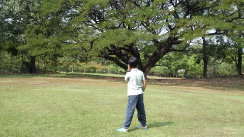 Active happy Asian little boy playing with a glider toy foam plane outdoors Stock Footage 337937202