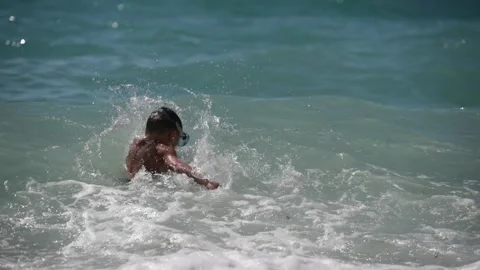 Active healthy little kid in diving mask playing with stormy waves in blue green Vidéo 160152383