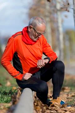 An Active jogging senior looking his smartwatch Foto stock