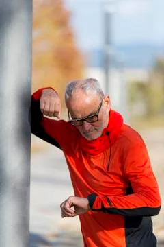 An Active jogging senior looking his smartwatch Stock Photos