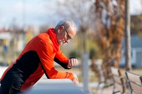 An Active jogging senior looking his smartwatch Stock-Fotos
