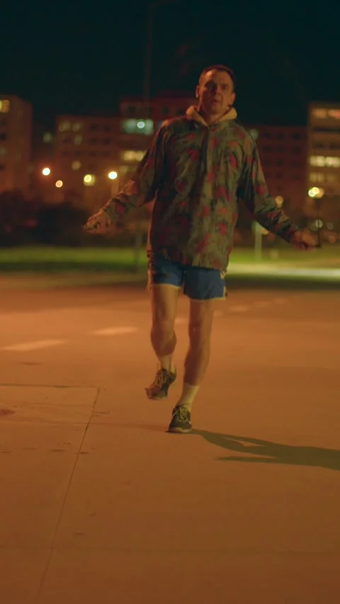 Active jump roping beneath luminous streetlights at night in city Stock-Footage 324592539