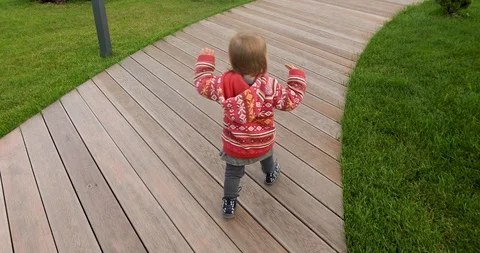 Active kid in red sweater walking on wooden path Vídeos de archivo 116092546
