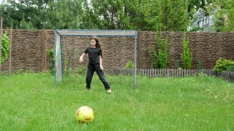 Active long-haired girl in dark clothing training and kicking a yellow soccer 스톡 동영상 330048768