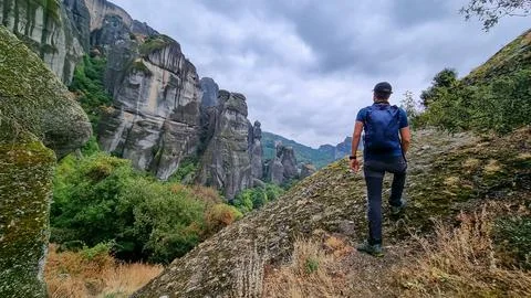 Active man with backpack standing under massive rock formation pinnacles ne.. Stock Photos