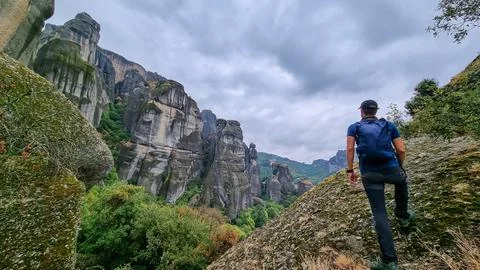 Active man with backpack standing under massive rock formation pinnacles ne.. Stock Photos