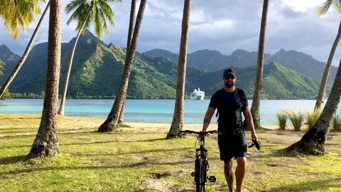 Active man with the bicycle walking from the beach in Opunohu bay Video stock 119578439