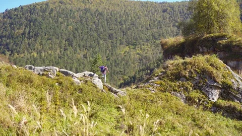 Active mаn climber with backpack gestures success after climbing the mountain Stock-Footage 95500252