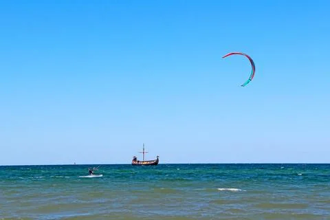Active man controls large colorful kite paraglide above sea water. Stock Photos