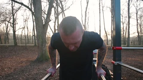 Active man doing push-up horizontal bar city park Increased muscle tone Sunlight Stock Footage 151342582