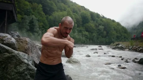 Active man is doing sport activities in nature, training hands punches, striking Video stock 163354748