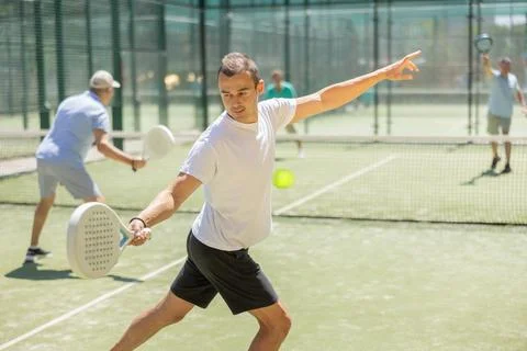 Active man with enthusiasm playing padel on tennis court Stock Photos