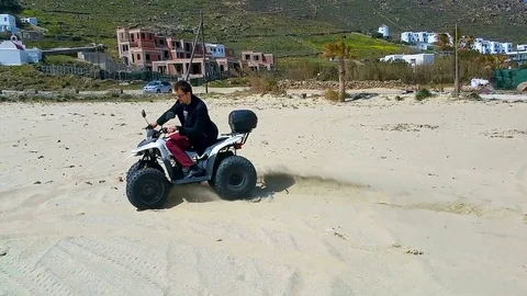 Active man having fun and getting extreme ride on quadcycle along sandy beach Stock Footage 84667614