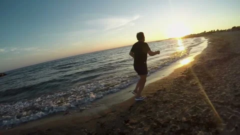 An active man is jogging on the seashore at sunset Stock Footage 136554329