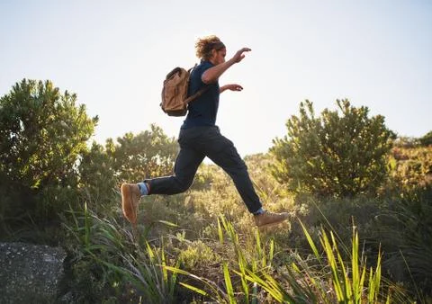 Active man jumping while hiking in mountains Stock Photos