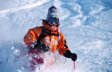 Active man in orange jacket skiing powder snow in the mountains in winter Stock Photos
