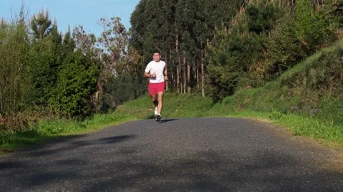 Active Man Running On Paved Country Road At Sunrise. Handheld Shot Stock Footage 310954801