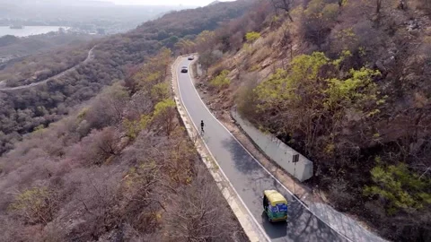 Active Man Running on Winding Mountain Road with Panoramic City Valley View 스톡 동영상 310463579