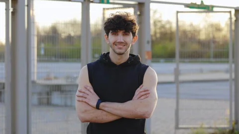 Active Man Strikes a Cross Hands Pose Amidst the Street Gym Equipment Stock Footage 258579859
