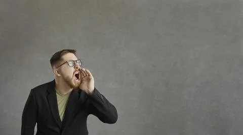 Active man who shouts, announcing advertising information standing on a gray Stock Photos