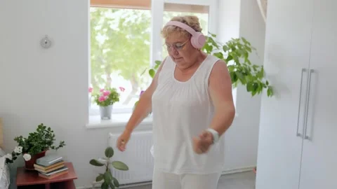 Active mature lady marching in place during home cardio exercise fitness at home 库存影片 337909231