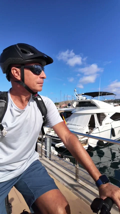 Active mature man enjoying riding an e-bike in a harbor Stock Footage 344816277