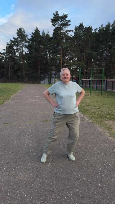 An active mature woman performs lateral stretching exercises on an outdoor  Stock Footage 338035961