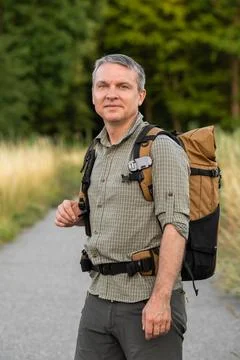 Active middle aged man on solo trekking journey, walking with backpack along  Stock Photos