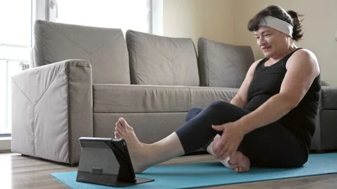 Active middle-aged woman practices yoga at home. A healthy lifestyle quarantined Stock Footage 130244365
