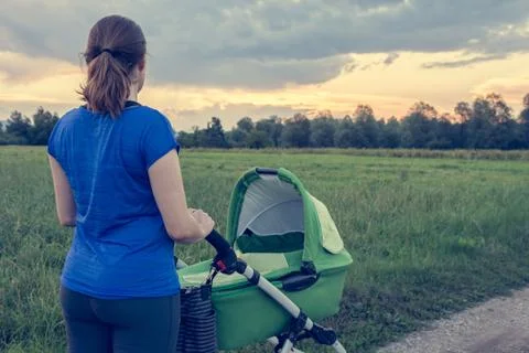 Active mom pushing a stroller at sunset. Stock Photos