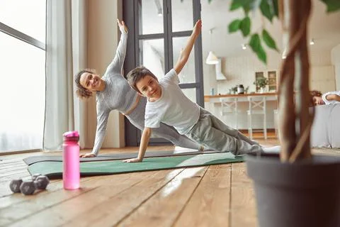 Active mother doing workout with son at home Stock Photos