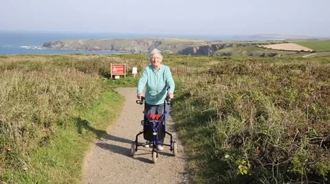 Active old lady pensioner walking with mobility aid on coast path Stock Footage 55034530
