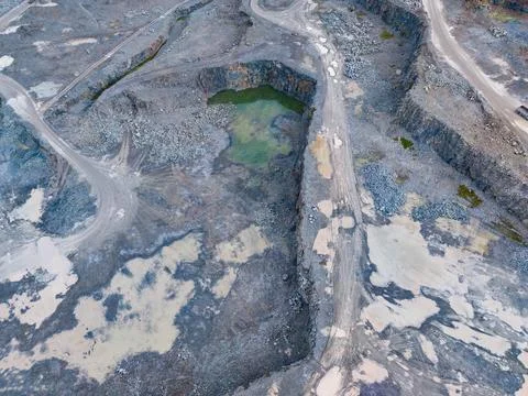 Active quarry site shows a large open pit with dirt paths and a small pond of Stock Photos