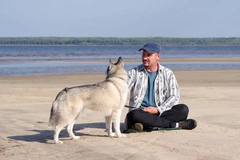 Active recreation, a 45-year-old man walks with a husky dog near a pond. Stock Photos