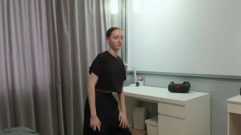 Active redhead girl dancing in white shirt and black pants in bedroom Stock Footage 326623200