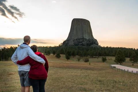 An active retired couple stand with backs to the camera looking at Devils Tow Stock Photos